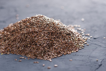 Flax seeds in a pile on a dark background. Concept healthy diet with omega 3 fatty acids.