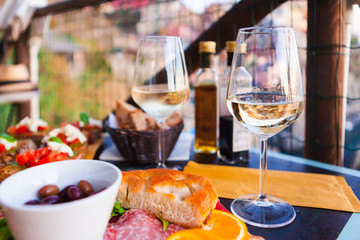 Romantic dinner for two at sunset. White wine and Tasty italian snack: fresh bruschettes  and meat on the board in outdoor cafe with amazing view in Manarola - 207134219