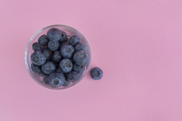 Blueberry in glass jar on pink background