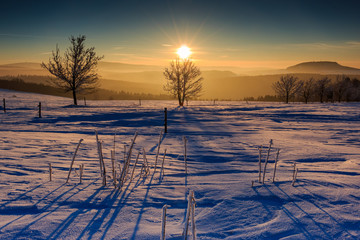 Sonnenuntergang im goldenen Sonnenlicht über dem winterlichen Erzgebirge. Blick zum Scheibenberg,...