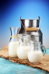 A jug of milk and glass of milk on a wooden table