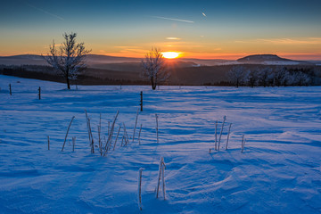 Sonnenuntergang im goldenen Sonnenlicht über dem winterlichen Erzgebirge. Blick zum Scheibenberg,...