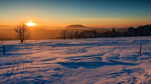 Sonnenuntergang im goldenen Sonnenlicht &uuml;ber dem winterlichen Erzgebirge. Blick zum Scheibenberg, Fichtelberg und Keilberg.