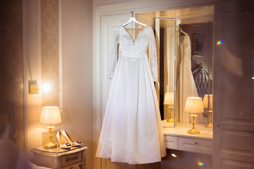 The perfect wedding dress with a full skirt on a hanger at the room of hotel of the bride room at wedding morning. Wedding bride's morning in Saint-Petersburg Russia. Honeymoon