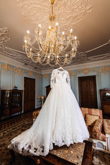The perfect wedding dress with a full skirt on a hanger at the room of hotel of the bride room at wedding morning. Wedding bride's morning in Saint-Petersburg Russia. Honeymoon