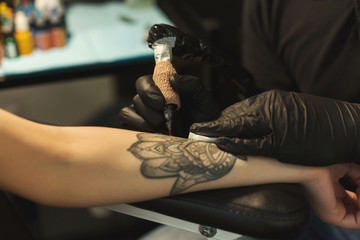 Professional tattoo artist making tattoo on hand