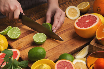 Female hands cutting citrus fruits on wooden board