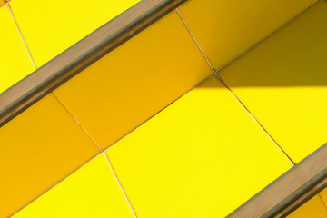 Abstract bright background - stairs of ceramic tiles of warm yellow, illuminated by the sun with darkened corners.