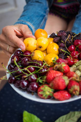 Buddha bowl full of ripe sweet fruits and berries. Loquat, cherry berries, black and white mulberry, strawberry. Raw vegan vegetarian healthy food dessert