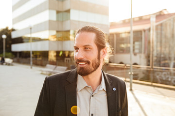 Closeup photo of corporate man or office manager in suit smiling, while standing in front of business centre in downtown