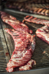 Fresh raw meat ribs with salt and pepper on big metal grill. Selective focus.1