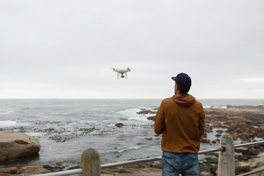 Man operating a flying drone near beach