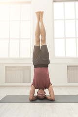 Young flexible man standing on hands