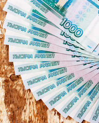 Russian banknotes in denominations of 1000 rubles are spread out on a fan on a wooden grunge background