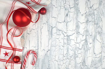Christmas background with napkin, red baubles, ribbon and a candy cane on rustic wood