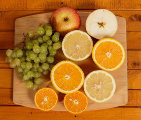 Grapes, lemon, orange,Apple, pear cut into slices on a wooden background.