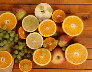 Grapes, lemon, orange,Apple, pear cut into slices on a wooden background.