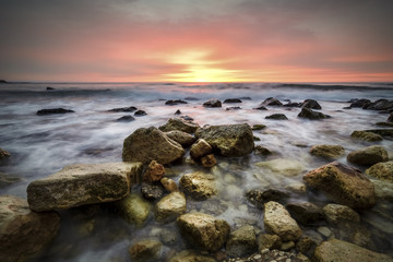 Seascape at sunrise with rocks and waves against a vibrant sky.Saint constantine and Elena beach.
