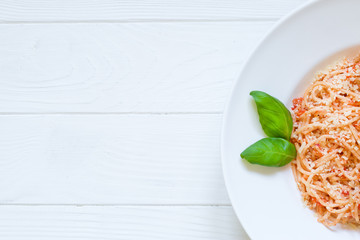 Tomato spaghetti with parmesan and basil on rustic wooden background. Top view. Copy space.