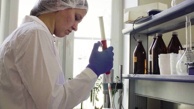 The scientist in laboratory adding water to the samples of the soil with chemical pipette