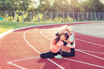 Athletic woman warming up before the race it at the stadium.