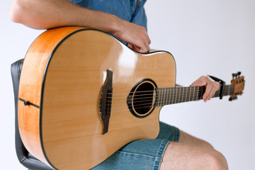 Fototapeta premium Handsome and cheerful guy musician in a shirt playing guitar