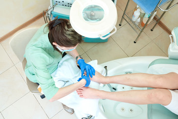Woman receiving cuticle in manicure pedicure salon. Patient on medical pedicure procedure, visiting podiatrist. Foot treatment in SPA salon. Podiatry clinic.