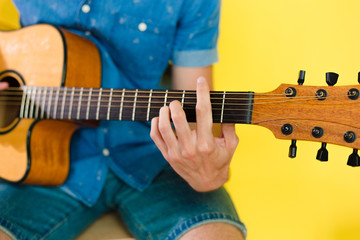 Obraz premium Handsome and cheerful guy musician in a shirt playing guitar