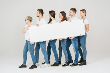 Group of friends in jeans holding a blank banner
