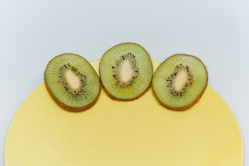 sweet ripe kiwi fruits on white, Kiwi cut into slices lay on a yellow plate, serving fruit