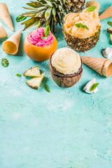 Summer holiday vacation concept, set various tropical ice cream sorbets, frozen juices in pineapple, grapefruit and coconut, light blue concrete background copy space