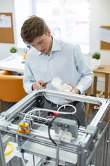 Precise data. Handsome young man figuring out the height of a model printed with a 3D printer while using a digital caliper