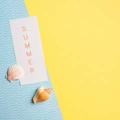 Modern minimal trendy summer yellow blue background symbolizing the sea and sand with shells and blank. flat lay concept of travel vacations. text summer on the sheet. Copy space, top view