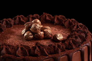Chocolate cake with nuts on a black background. Close-up