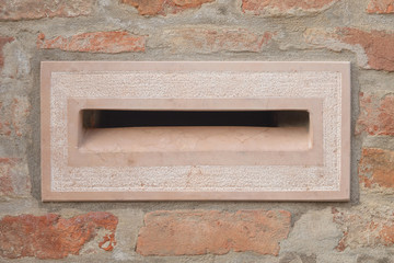 mail box in pink marble, on a  wall of briks
