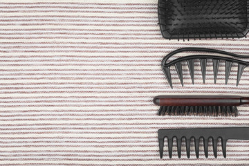 set of various professional hairbrushes lying on a grey striped background. concept of professional hairdresser tools. free space for text