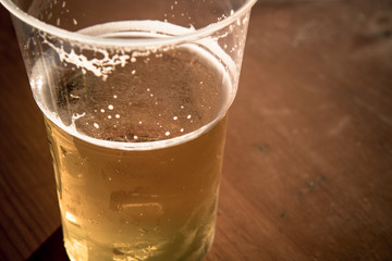 plastic glass of beer, focus on beverage on wooden background
