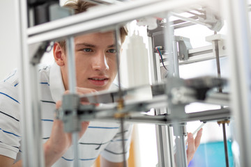 Exciting process. Pleasant young man watching skyscraper model being made with the help of a 3D...
