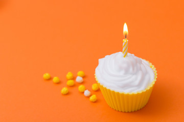 yellow birthday cupcake on an orange background