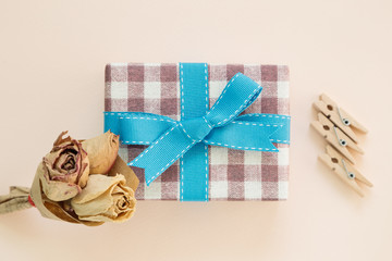 Gift box and dry rose on pink background