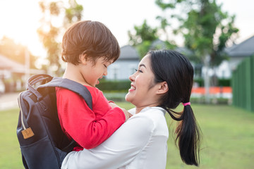 Mom hug and carry her son. Preparing to send her children back to school in morning. Mother playing with kids. Education and Back to school concept. Happy family and Loving of people theme