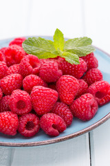 Fresh raspberries in a plate on a  vintage background.