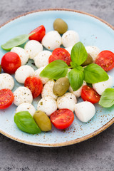 Delicious caprese salad with ripe cherry tomatoes and mini mozzarella cheese balls with fresh basil leaves.