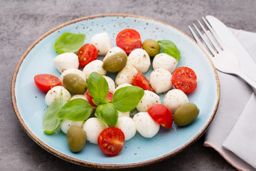 Delicious caprese salad with ripe cherry tomatoes and mini mozzarella cheese balls with fresh basil leaves.