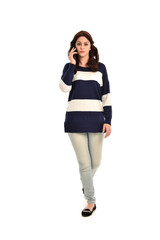 full length portrait of girl wearing striped blue and white jumper and jeans, holding a phone. standing pose on white studio background