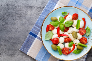 Delicious caprese salad with ripe cherry tomatoes and mini mozzarella cheese balls with fresh basil leaves.