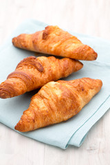 Tasty buttery croissants on old wooden table.