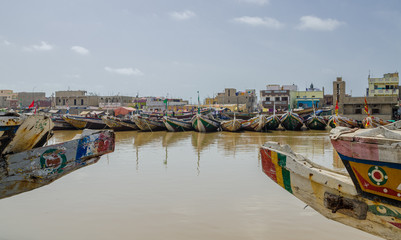 Fototapeta na wymiar St Louis, Senegal - October 12, 2014: Colorful painted wooden fishing boats or pirogues at coast of St. Louis