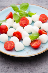 Delicious caprese salad with ripe cherry tomatoes and mini mozzarella cheese balls with fresh basil leaves.
