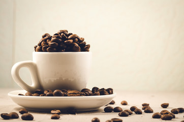 white cup full of coffee beans/white cup full of coffee beans on a concrete background, selective focus and copy spce